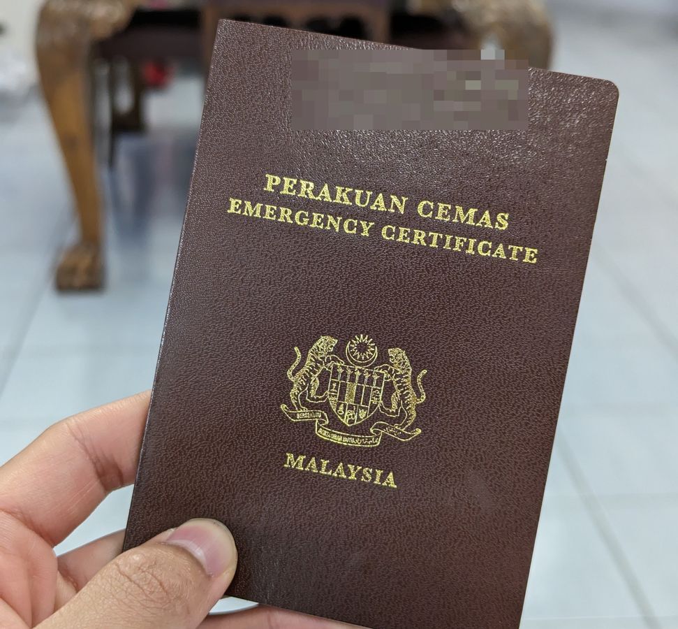 A picture of a Malaysian Emergency Certificate being held up by hand, issued in the year 2024 by the Malaysian Embassy in Bucharest, Romania